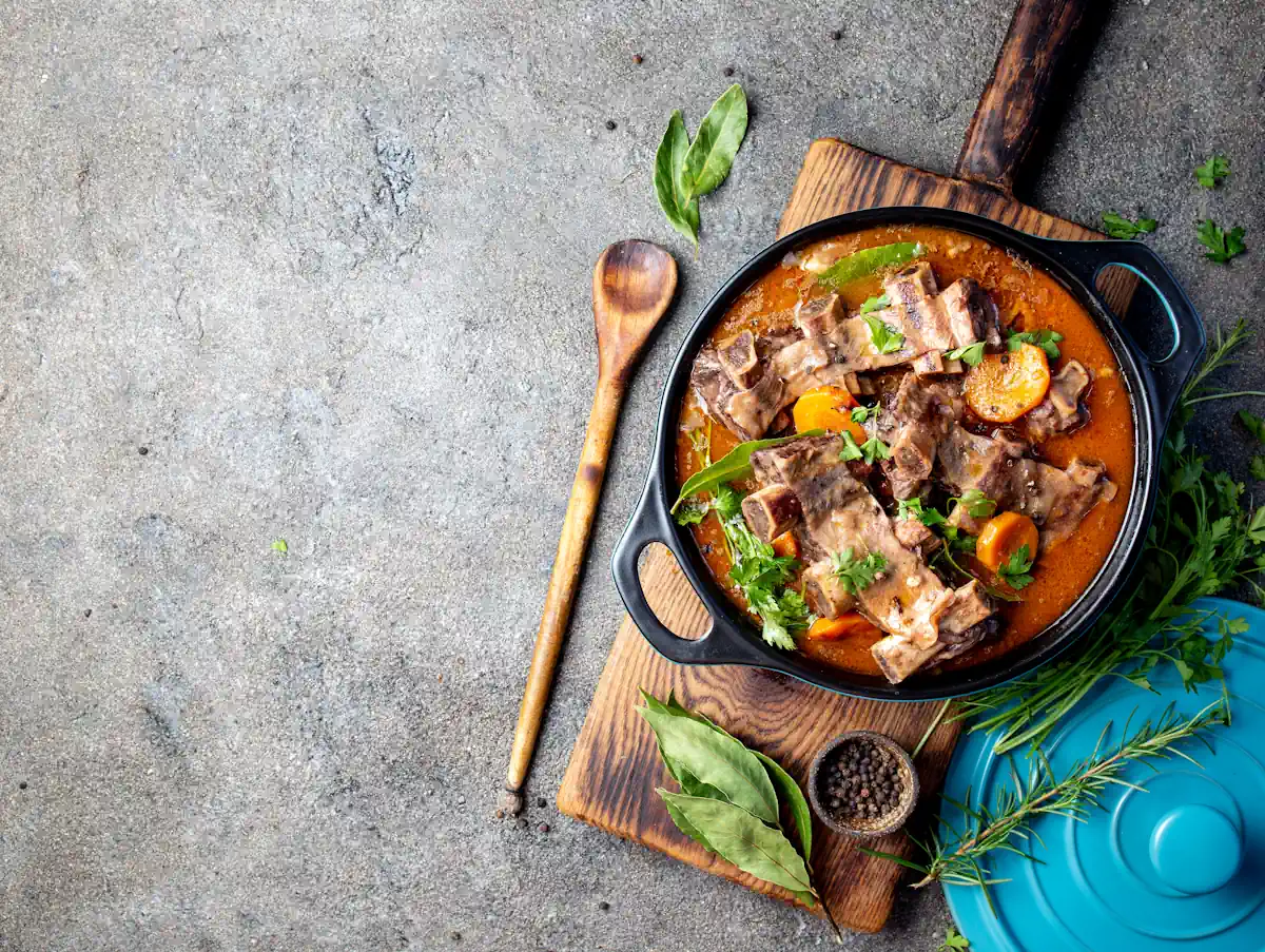 Un plat de boeuf bourguignon posé sur une plaque de bois dans une marmite