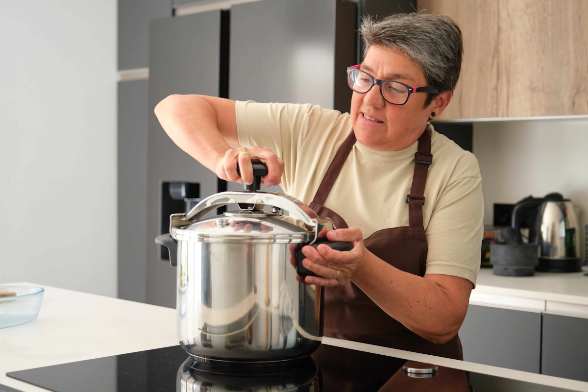 Une femme qui serre sa cocotte minute posée sur une plaque à induction