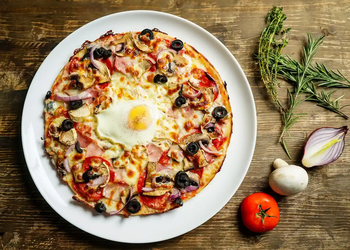 Un pizza sur une assiette posée sur la table avec un oeuf sur le dessus