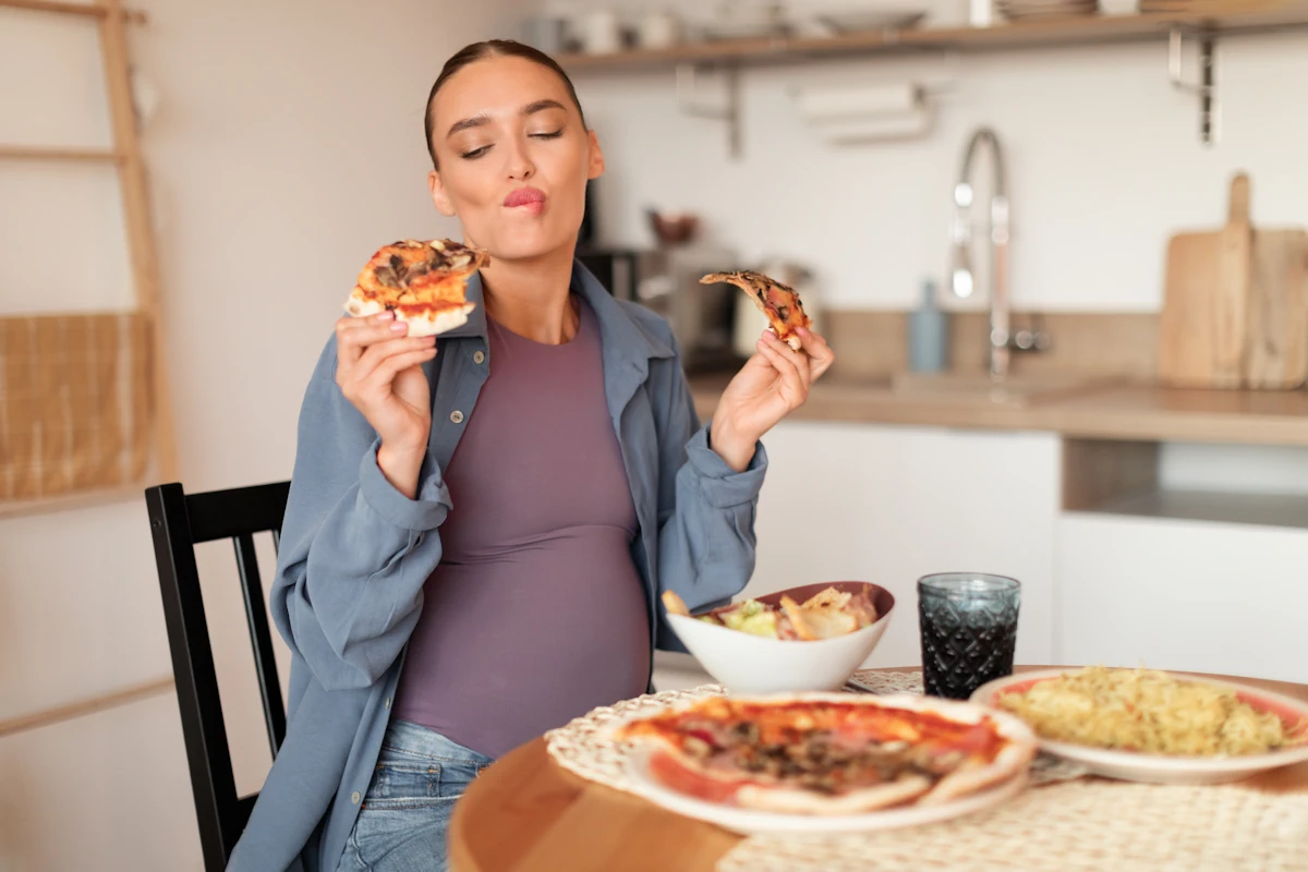 Une femme enceinte qui mange une pizza à table