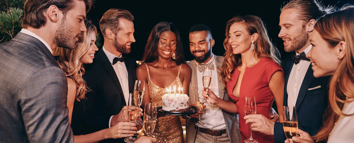 Une jeune femme qui tient un gâteau d'anniversaire entouré par ses amis