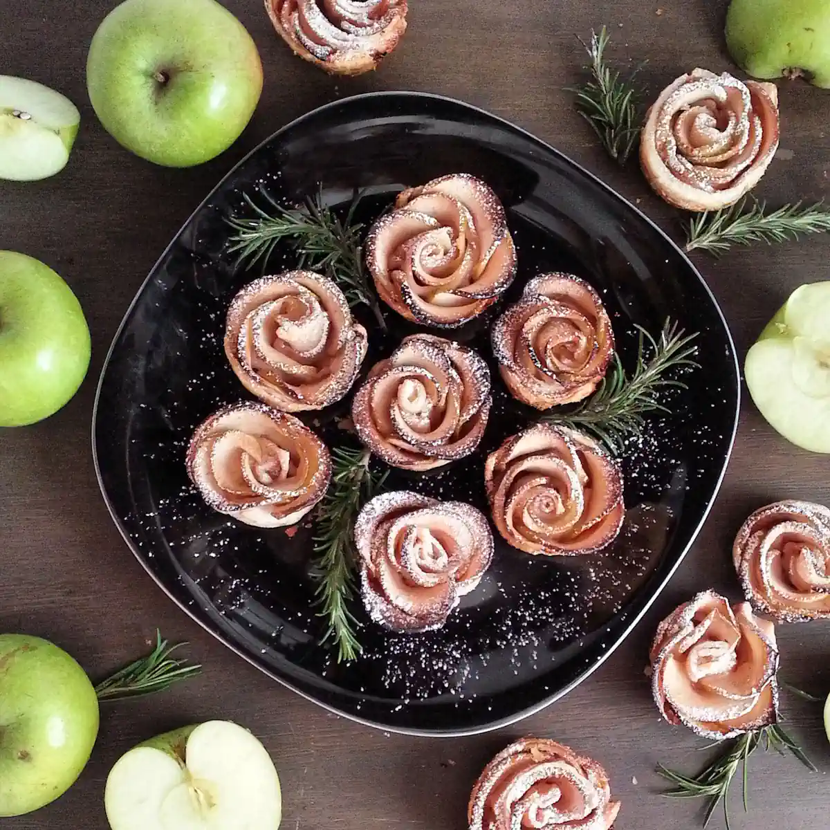 Une assiette de roses des sables posés sur une table à côté de quelques pommes