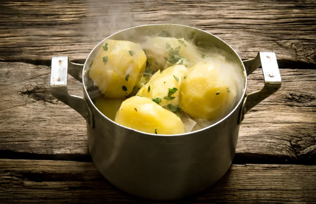 Pomme de terre dans une casserole posée sur une table en bois