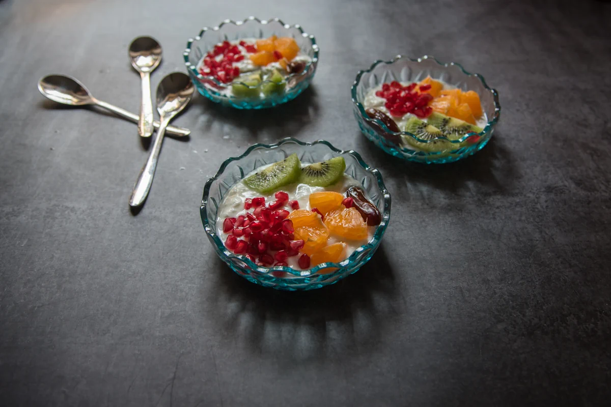 3 bols de salade de fruits posés sur une surface grise avec 3 cuillères
