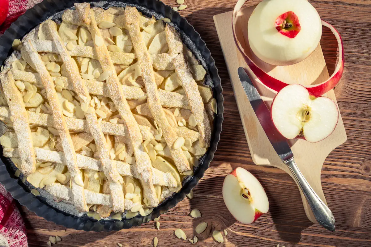 Une tarte aux pommes posée à côté de quelques pommes fraîchement coupées