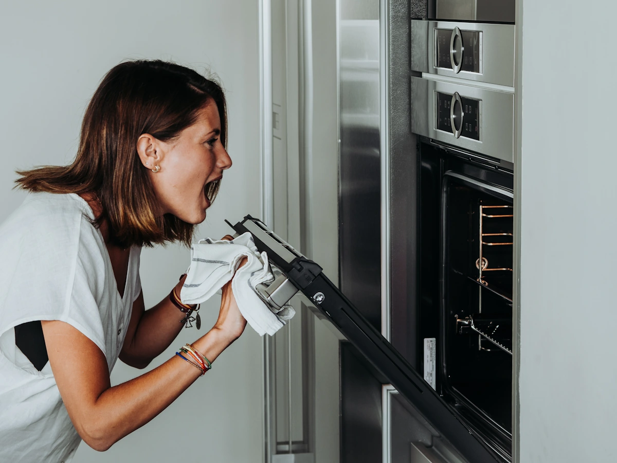 Une femme qui regarde à l'intérieur de son four en criant