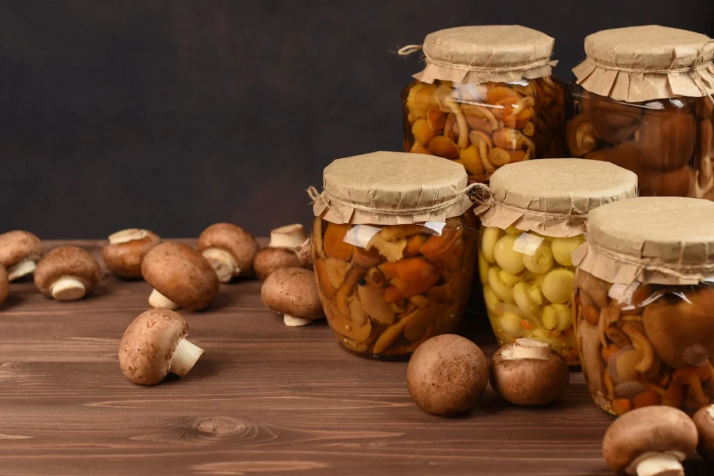 Bocaux de champignons posés sur une table à côté de quelques champignons