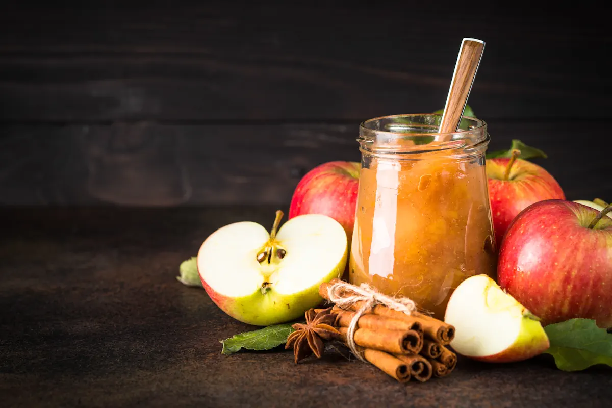 Un bocal de compte de pommes à côté de pommes et de quelques bâtons de cannelles
