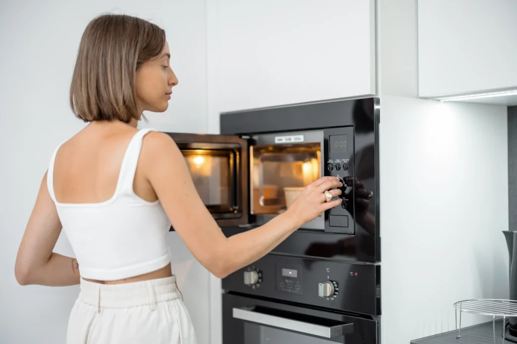 Une femme qui met un plat dans un micro-onde