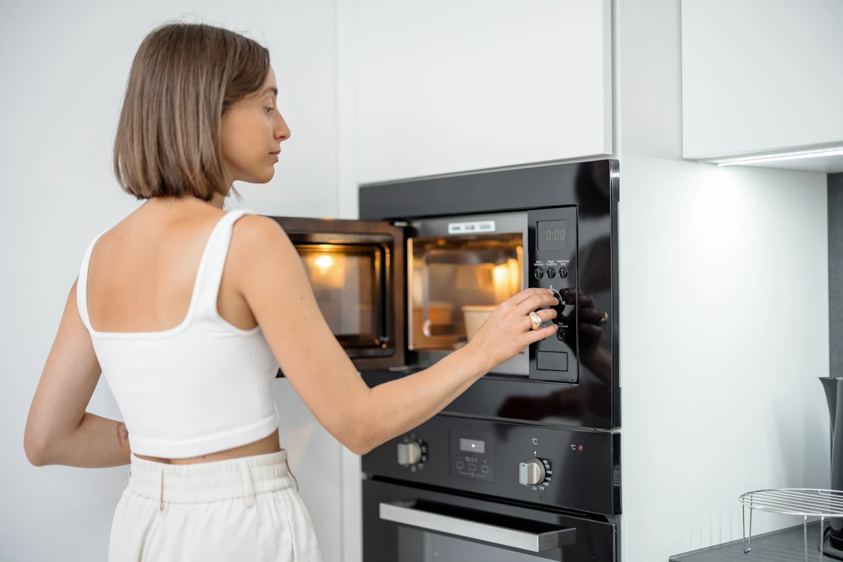 Une femme qui met un plat dans un micro-onde