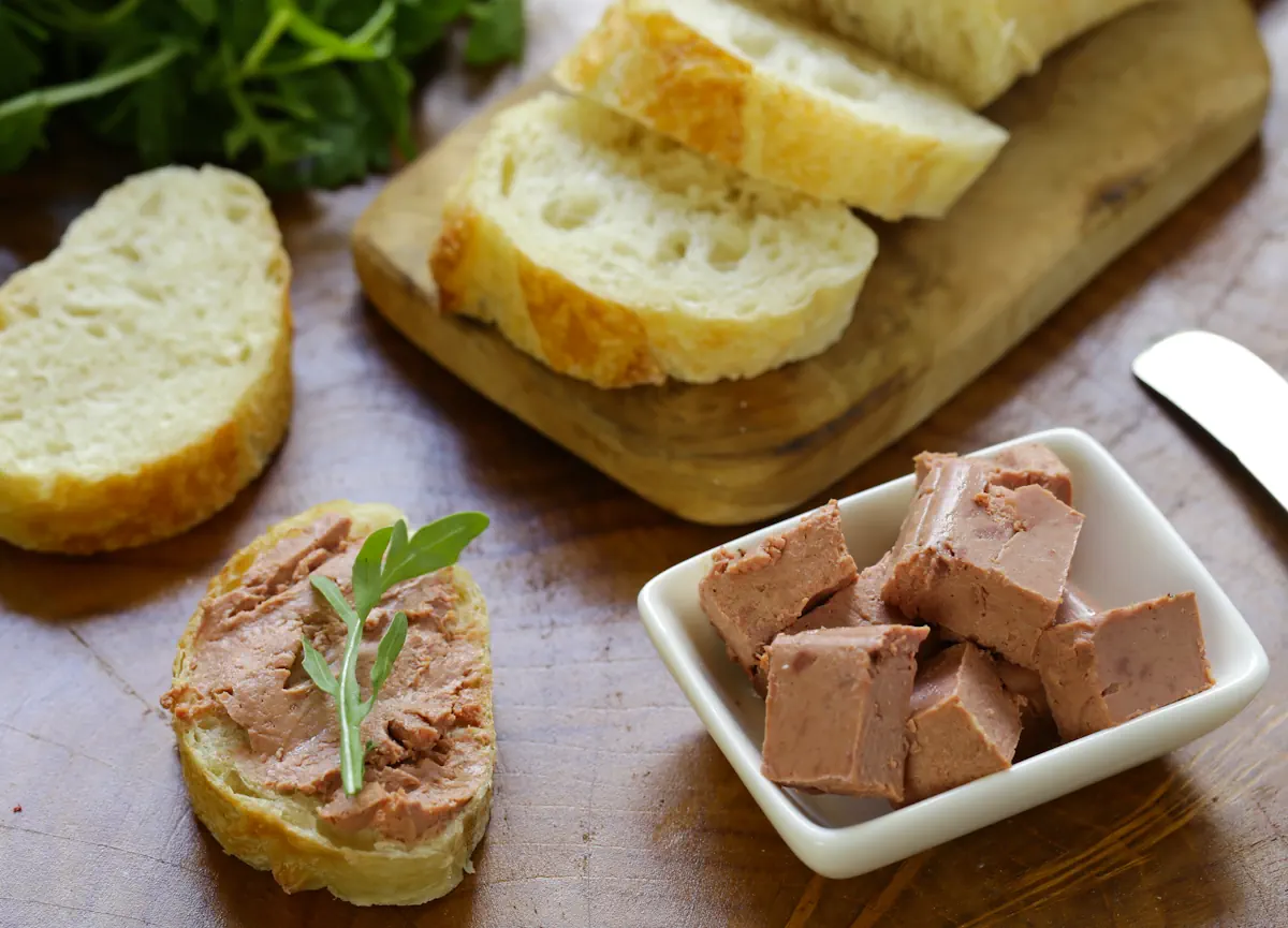 Une assiette pleine de mousse de canard avec des pains posés à côté