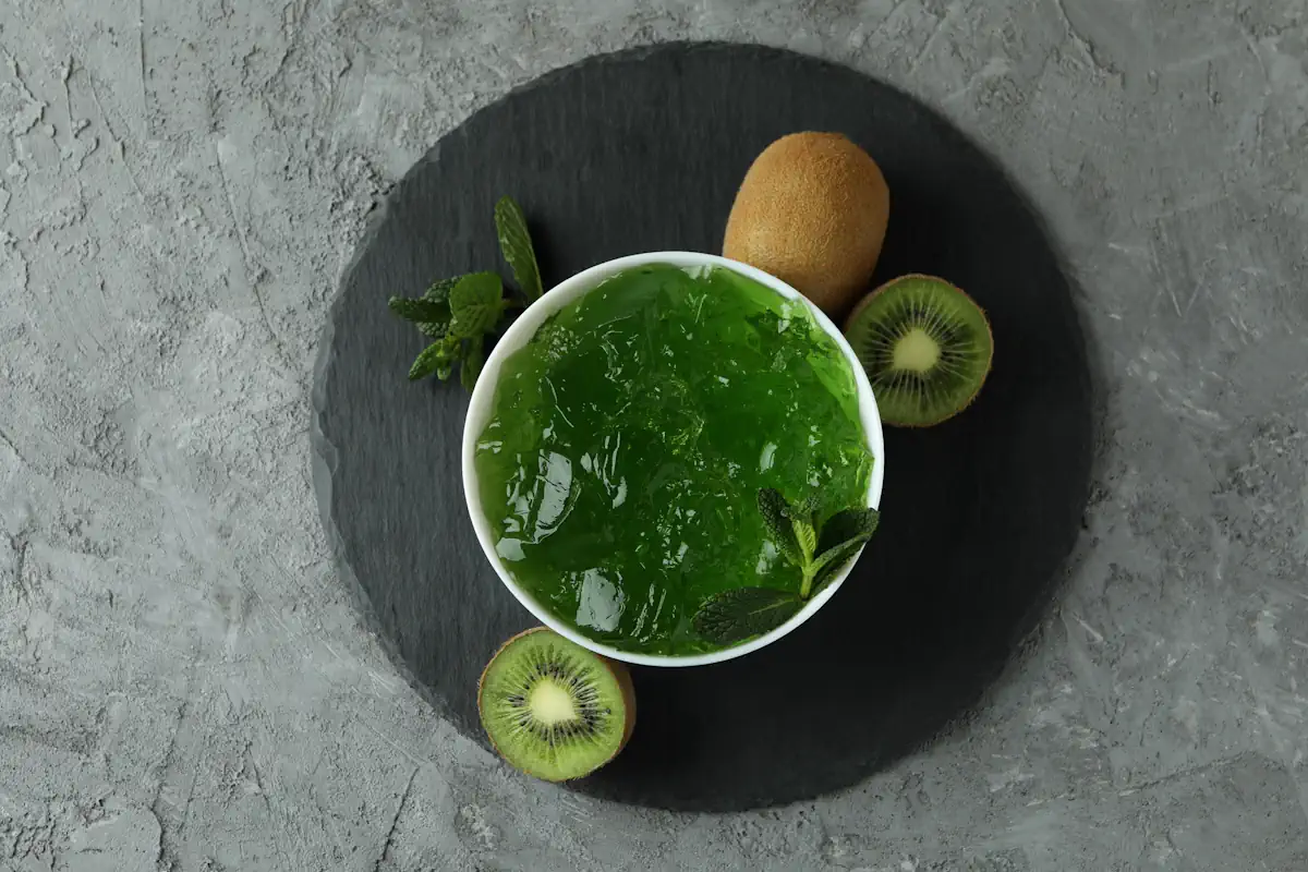 Un bol de gélatine verte entouré de kiwi