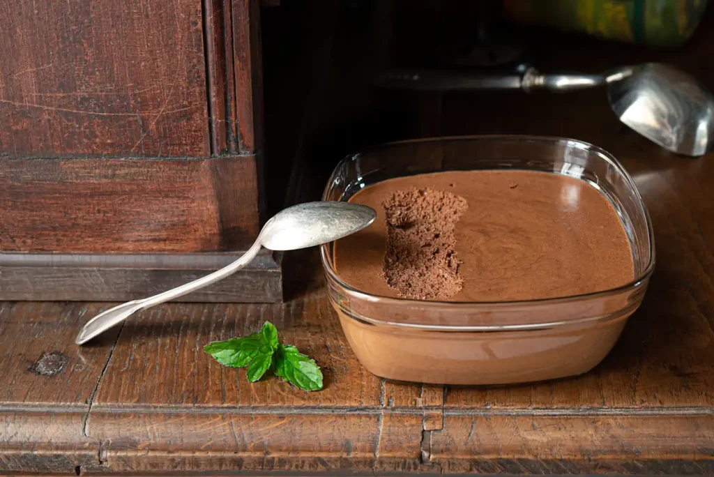 Un bol en verre carré contenant de la mousse au chocolat avec une cuillière