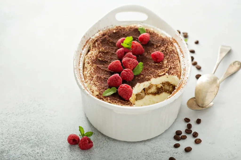 Un pot de tiramisu avec du cacao et des framboises sur le dessus