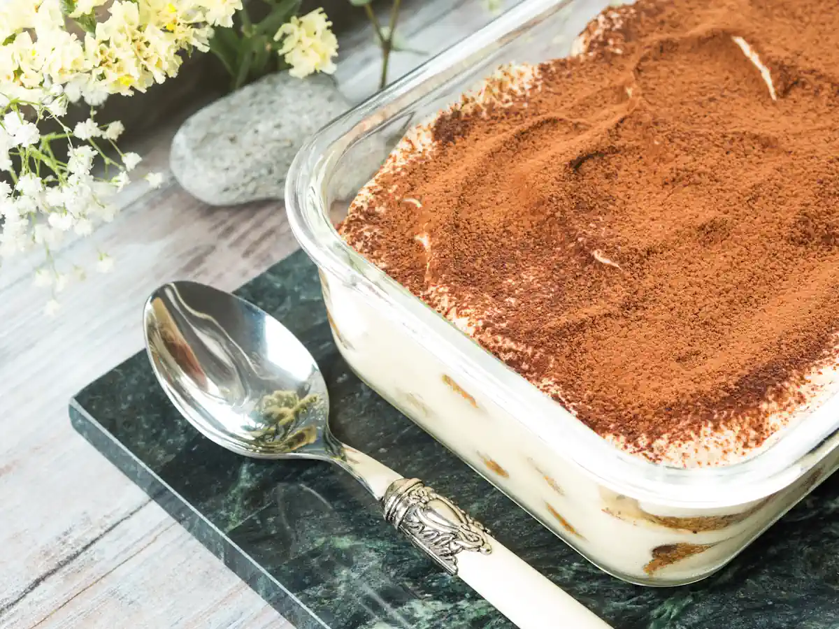 Un tiramisu dans un plat à côté d'une cuillière