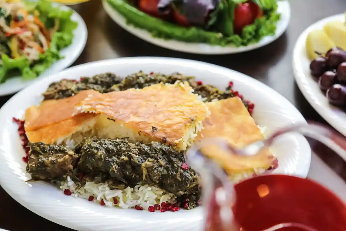 Une assiette avec des feuilles de mloukhia du poisson posé à côté de plusieurs autres plats