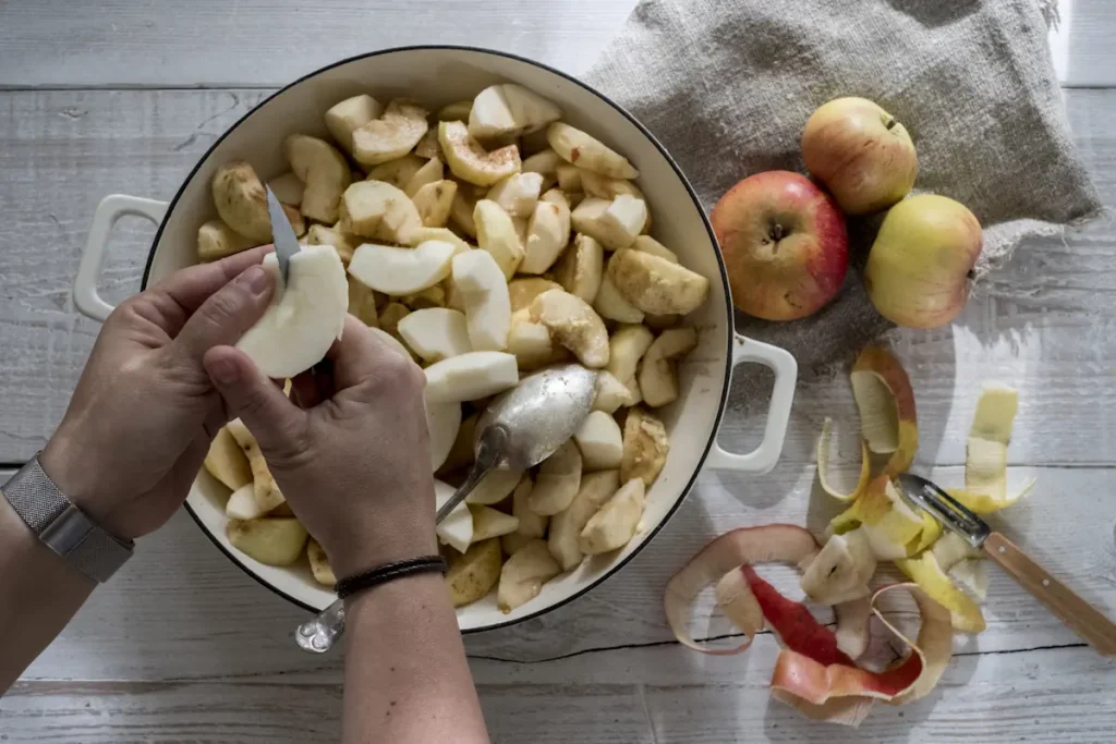 une personne qui coupe des pommes dans une marmite