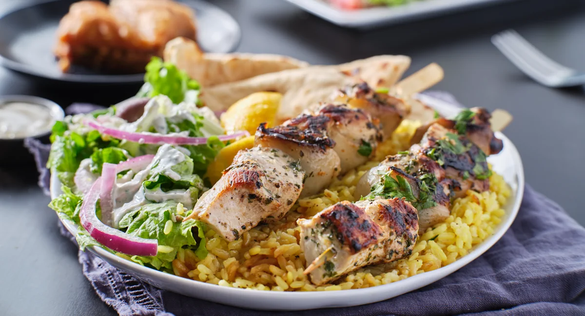 Une assiette de brochette de poulet avec du riz et de la salade