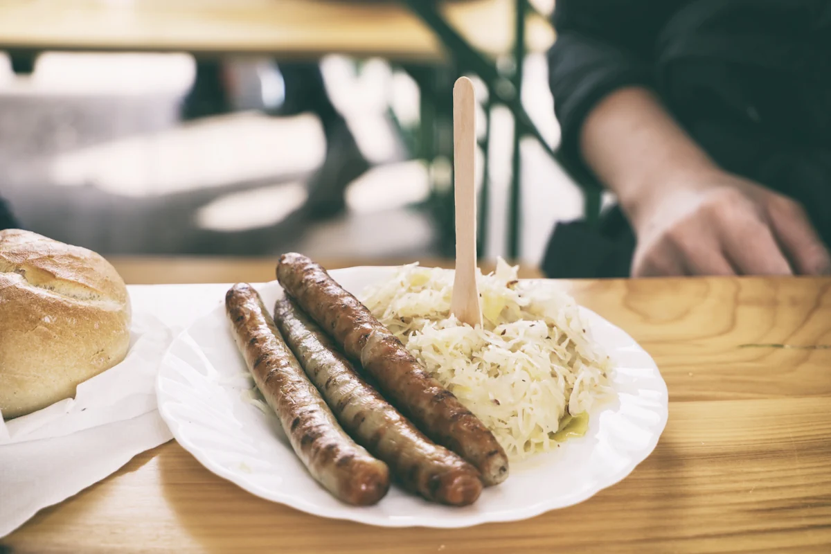 Une choucroute saucisse sur une assiette blanche avec une fourchette en bois