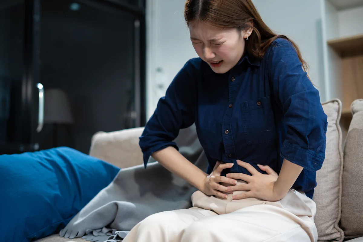 Une femme qui se tient le ventre en faisant une grimace