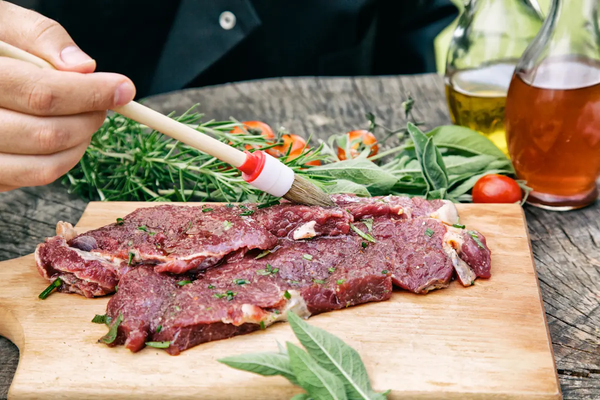 Une personne qui applique quelque chose sur une viande de boeuf avec un pinceau