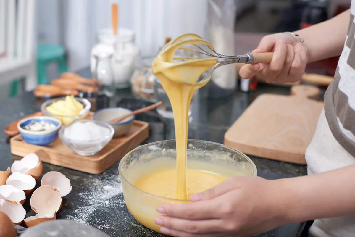 Une personne qui mélange de la pâte à crême avec un fouet