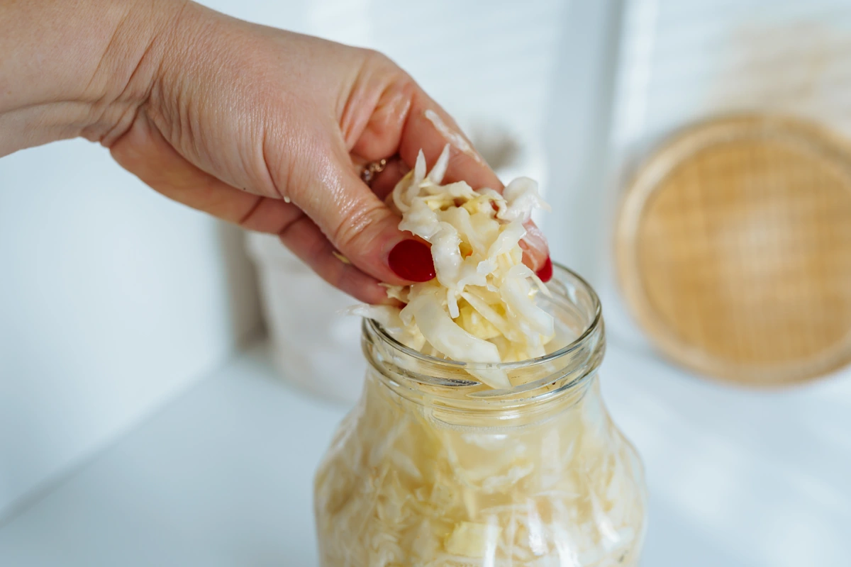 Une personne qui verse de la choucroute dans un bocal en verre