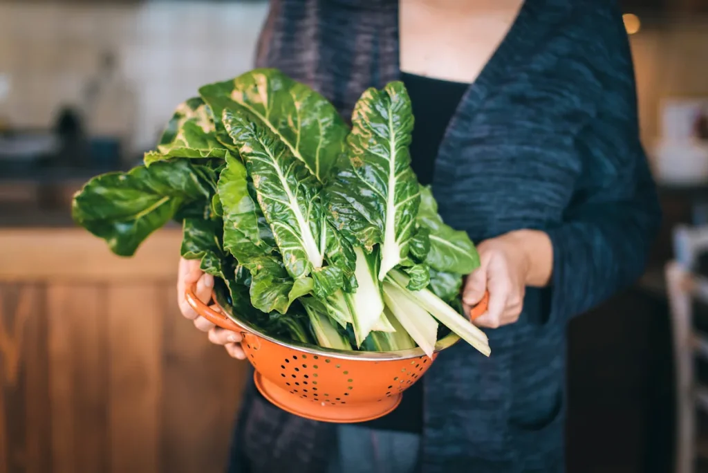 Une femme qui tient un saladier avec des légumes à feuilles vertes