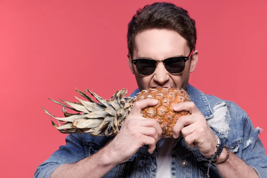 Un homme qui mange un ananas