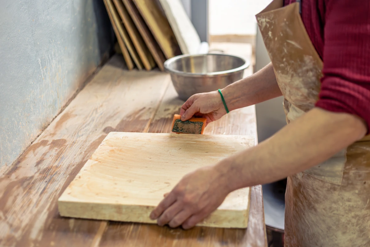 Une femme qui tient une planche à découper en bois épais