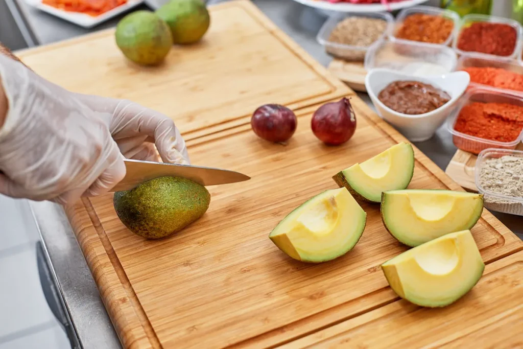 Une personne qui coupe des avocats sur une planche à découper à bois