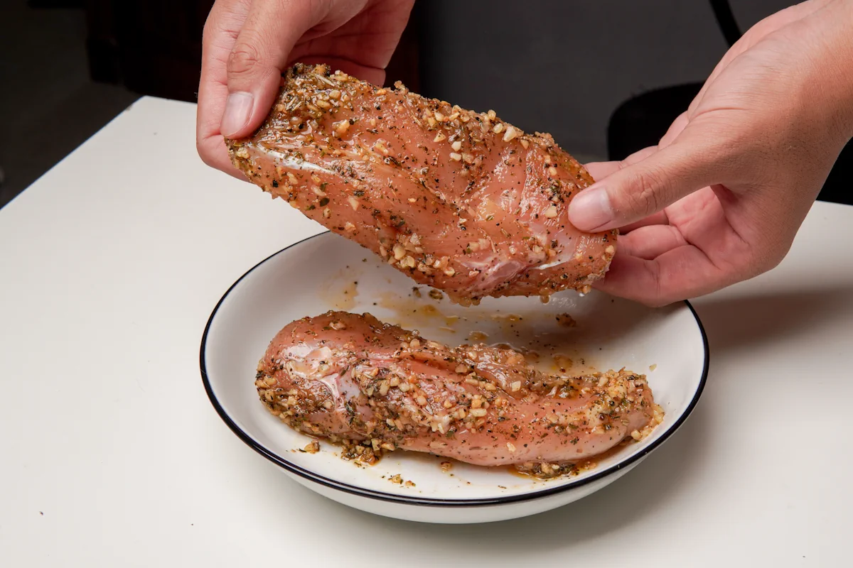 Un homme qui prépare une assiette de poulet avec de la marinade