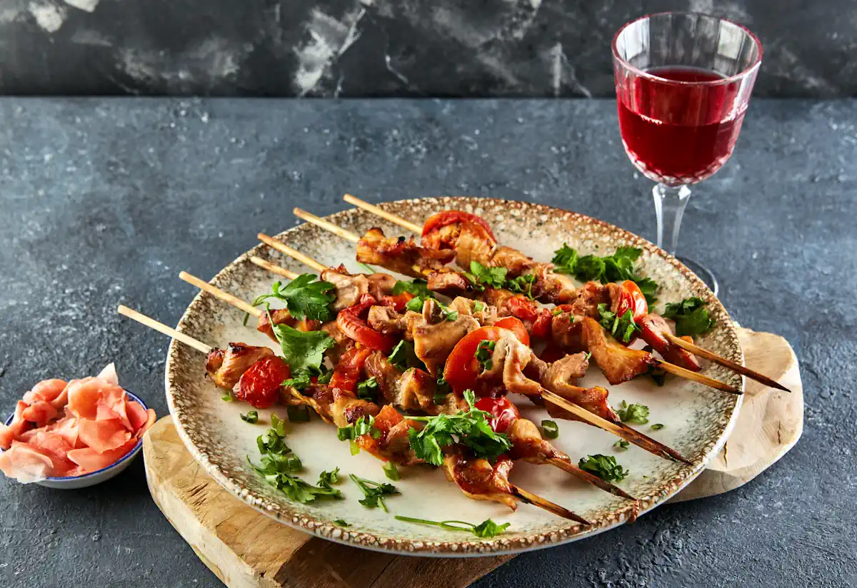 Une assiette de brochette de poulet posée à côté d'un verre de vin