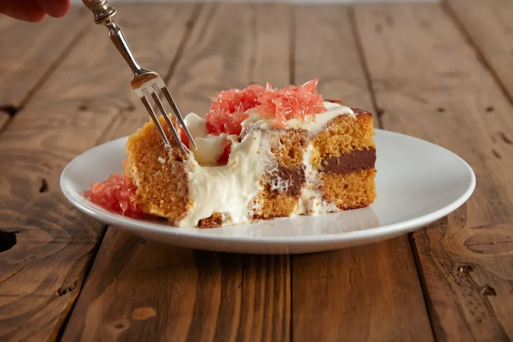 Une personne qui prend un morceau de gâteau dans une assiette blanche avec une fourchette