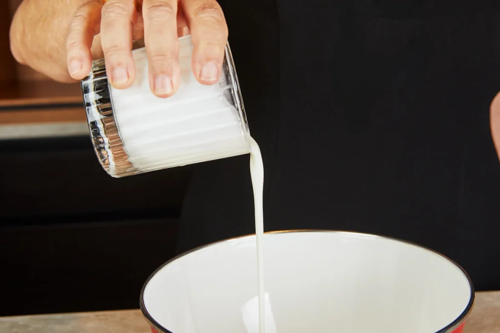 Une personne qui verse du lait dans un bol