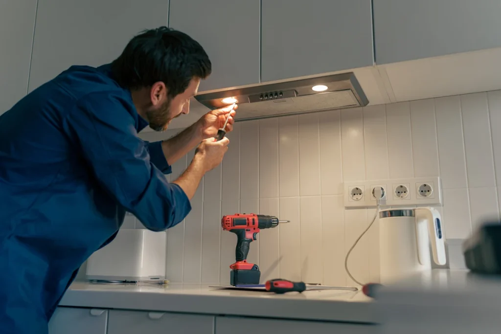 Un homme qui installe des spots LED sur pour éclairer un plan de travail de cuisine