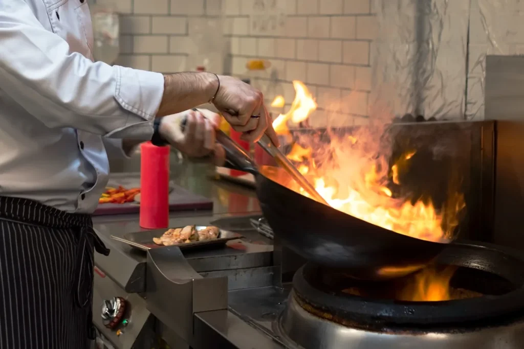 Un homme qui faitle cullotage d'un wok en acier en carbonne
