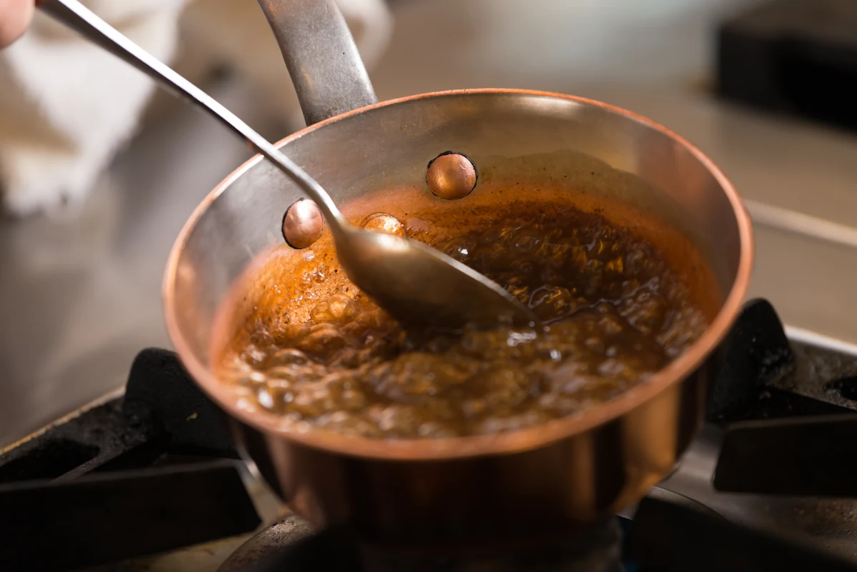 Une personne qui fait fondre du caramel dans un casserol
