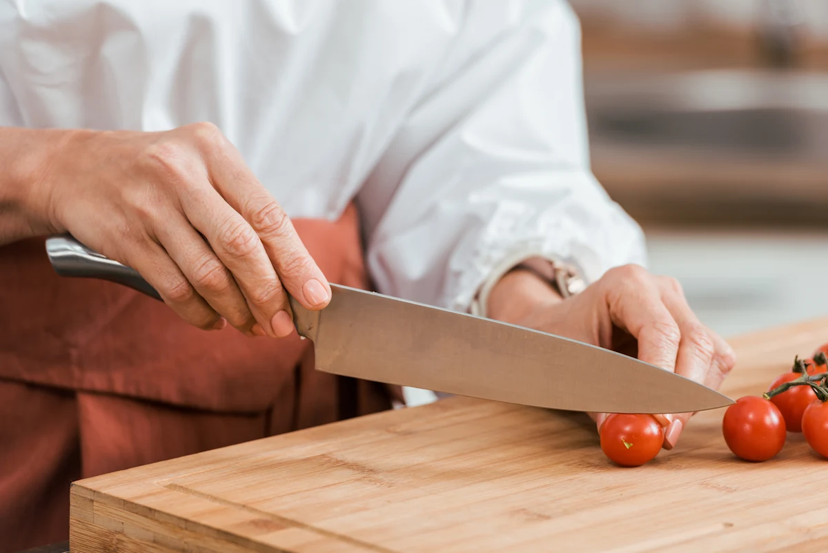 Un chef qui utilise un couteau pour coupe une tomate