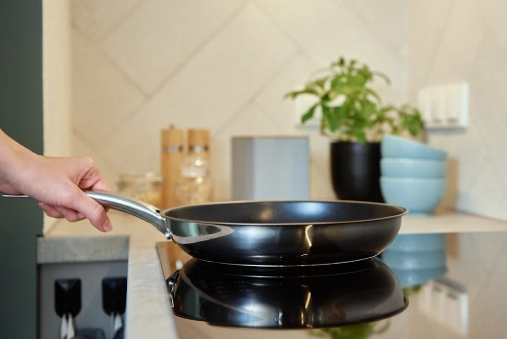 Une personne qui cuisine avec une poêle en inox