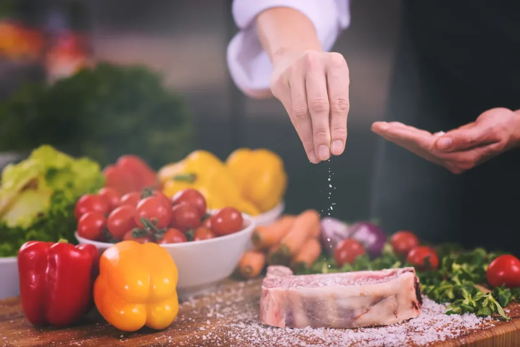 Une femme qui sale de la viande avant la cuisson
