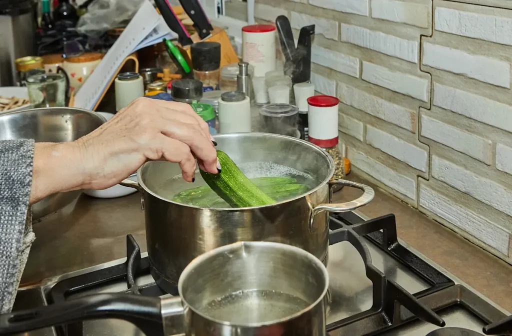 Une personne qui blanchit des légumes dans l'eau bouillante