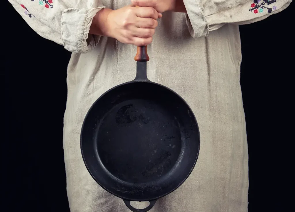 Une personne qui tient une poêle en fonte
