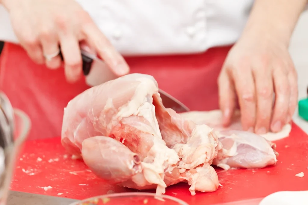 Une personne qui désosse un poulet entier avec un couteau
