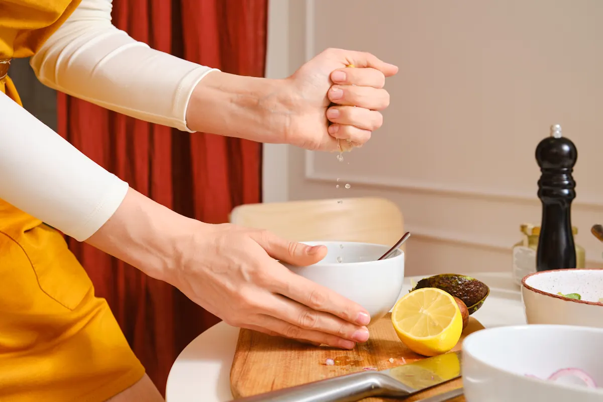 Une personne qui verse un filet de jus de citron dans une sauce
