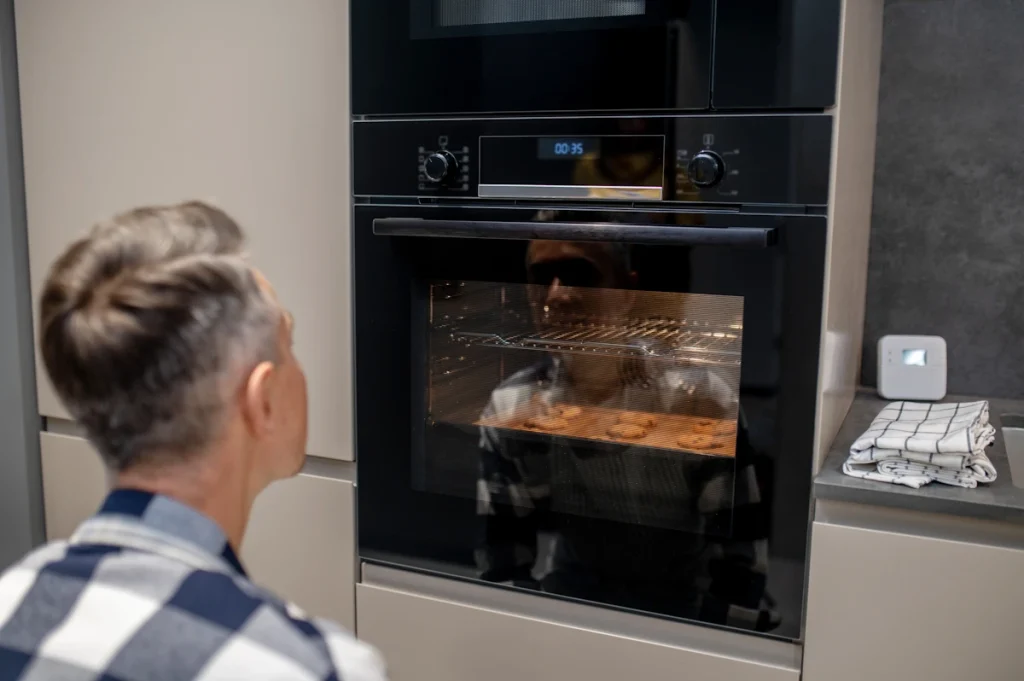 Un homme qui surveille un plat qui cuit au four