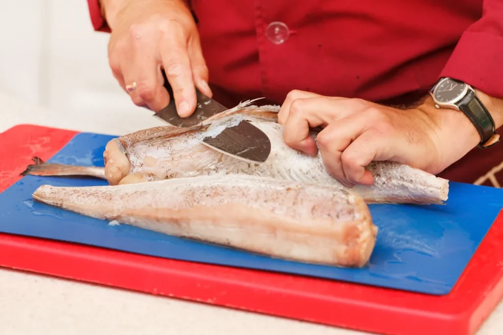 Une personne qui enlève les arrêtes d'un filet de poisson avec un couteau