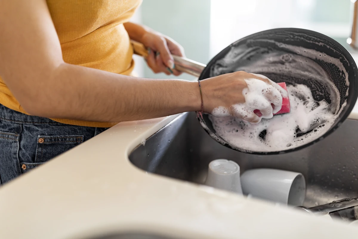 Une personne qui lave un wok en acier carbone