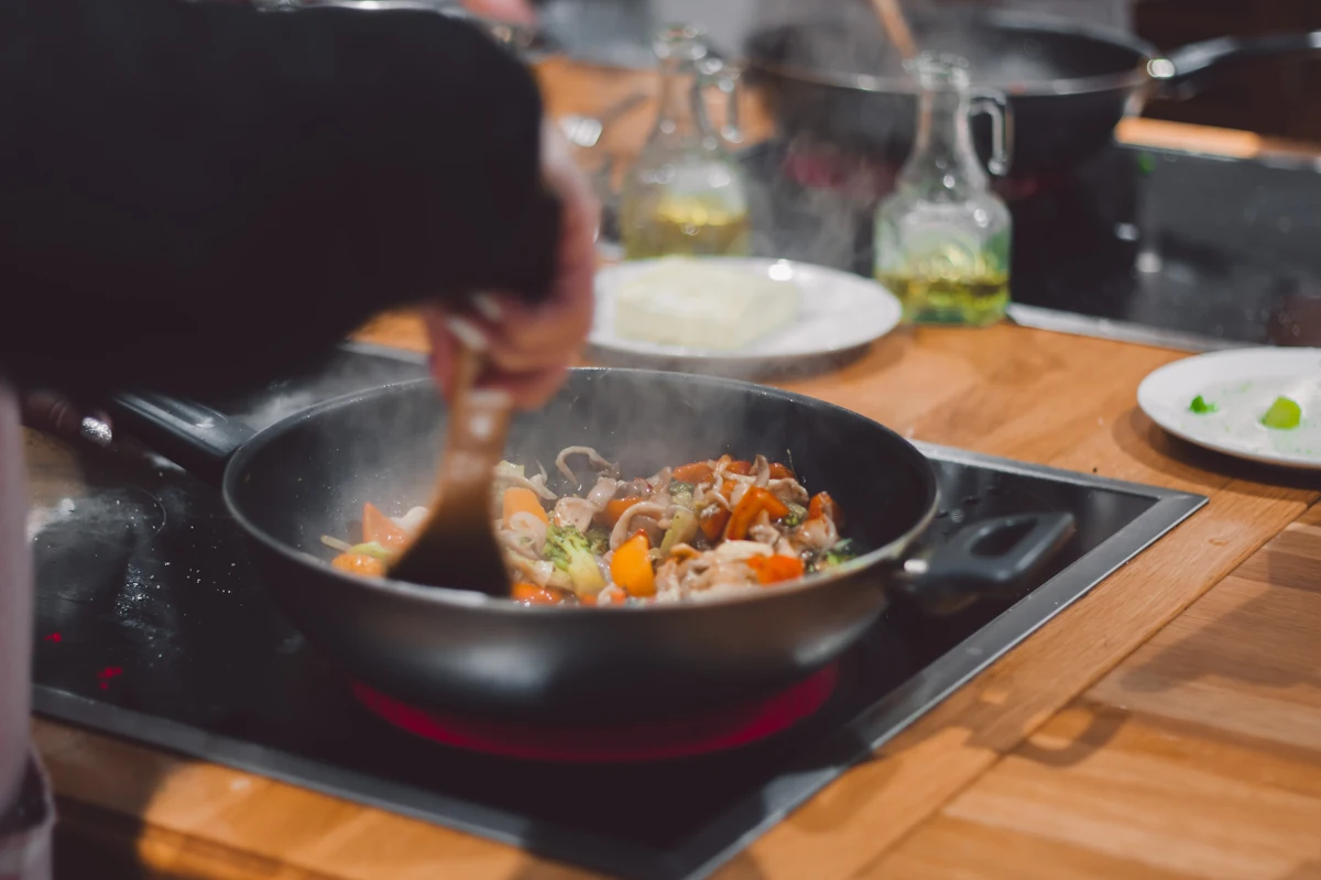 Une personne qui cuisine avec un wok à fond plat